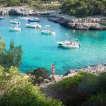 woman in red bikini standing on the shore besides water