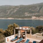 aerial view of pool lounge and body of water near mountain